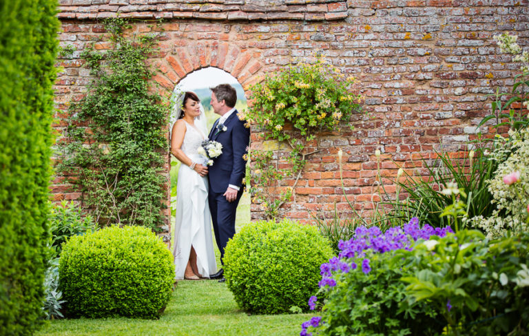 A bride and groom standing in a garden.
