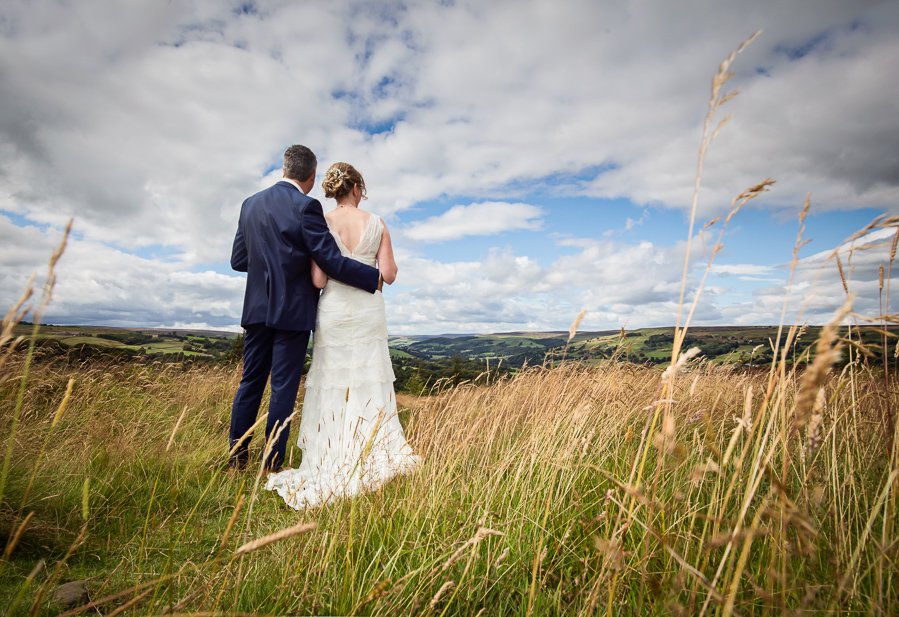 A bride and groom standing in tall grass.