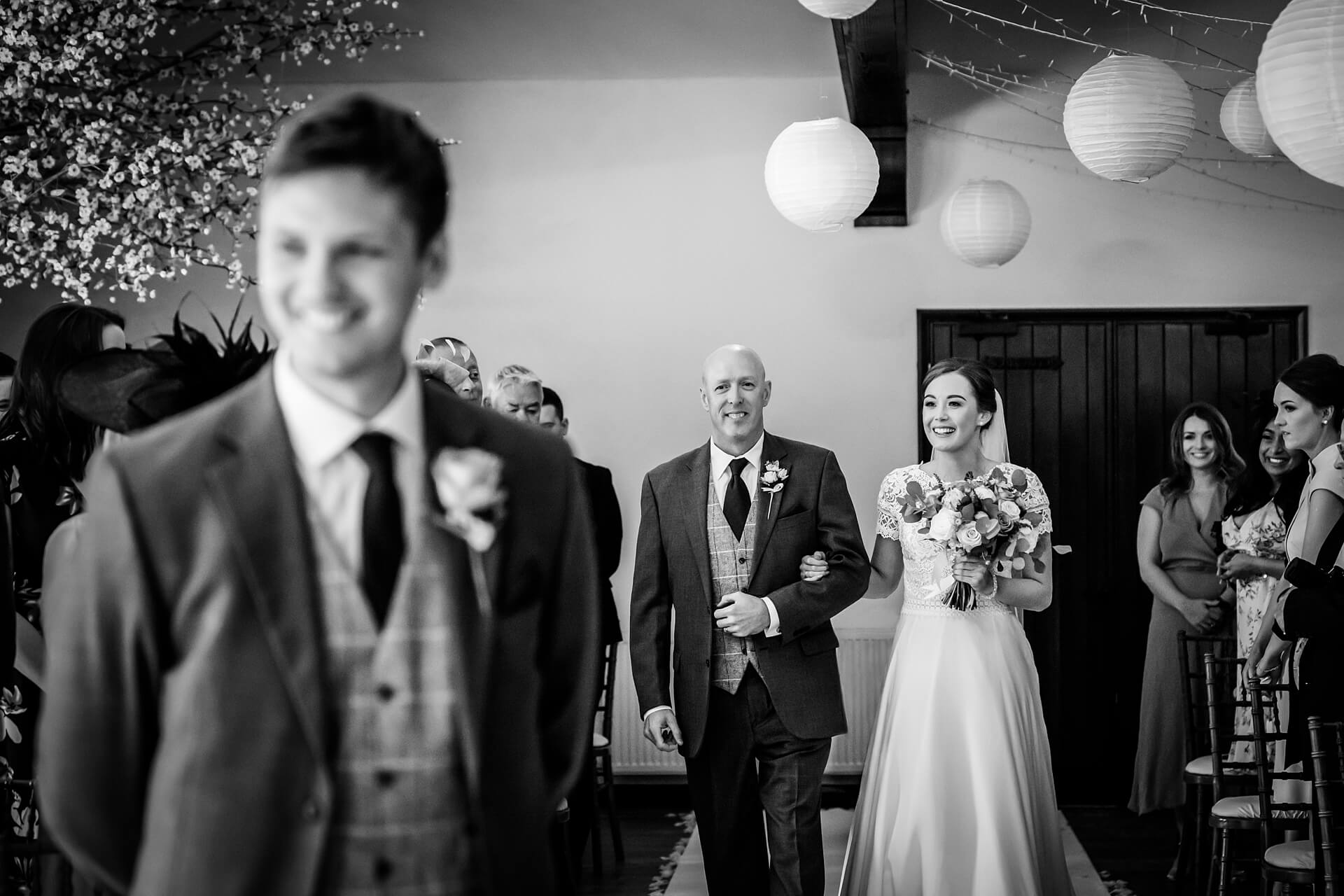 Bride and groom smiling as they walk down the aisle after their wedding ceremony, with guests looking on.