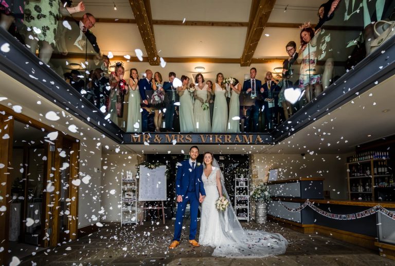 Newlyweds celebrating with guests throwing confetti at their wedding reception.