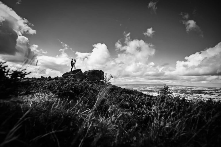Person standing on a rocky outcrop against a dramatic sky.