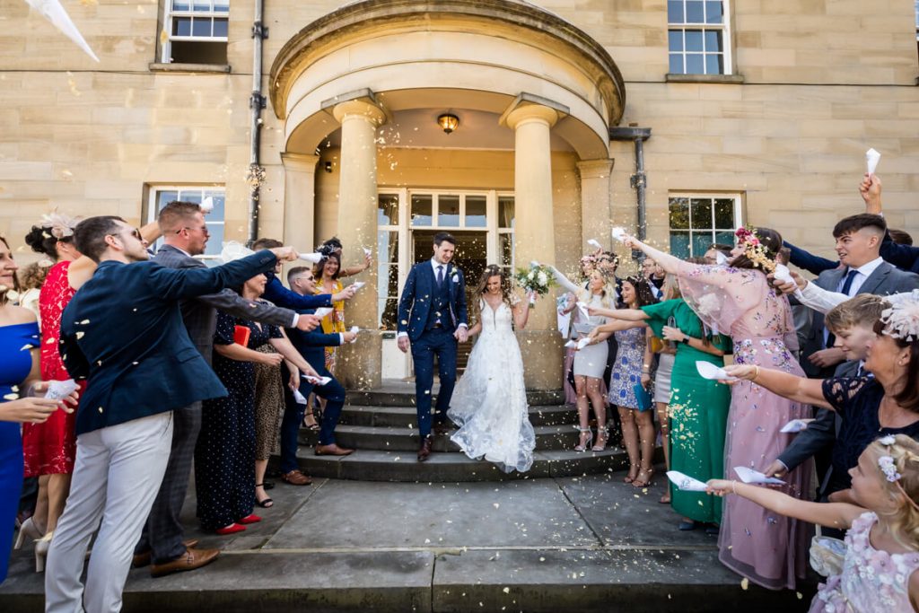 Bride and groom being showered with confetti in front of Saltmarshe Hall