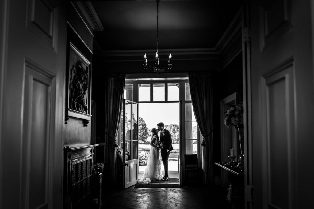 Silhouette of the bride and groom kissing in the doorway to Saltmarshe Hall
