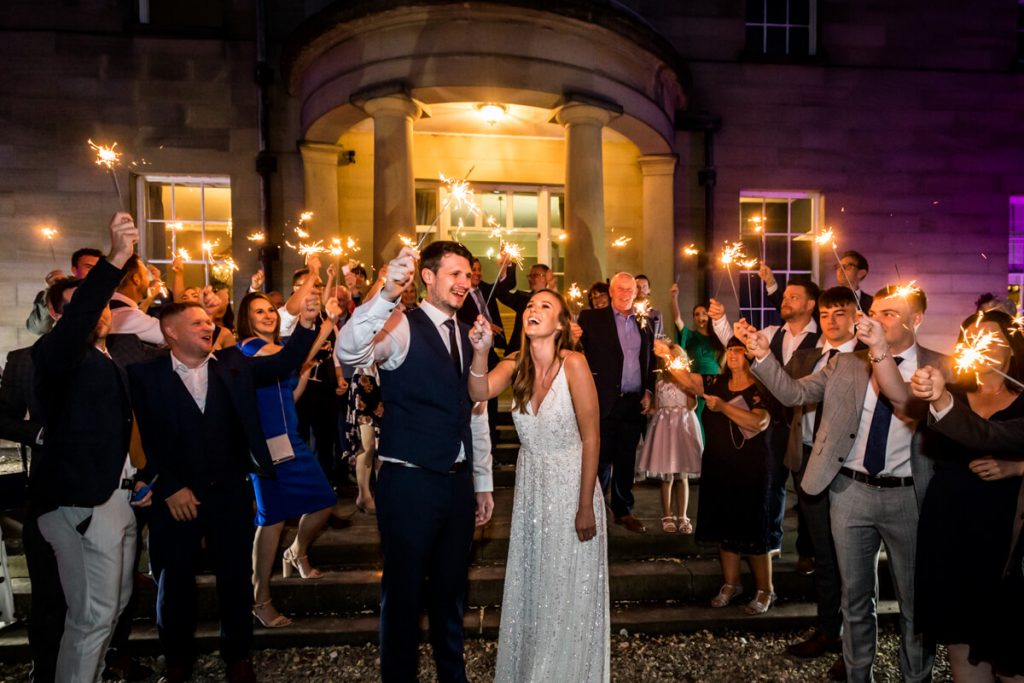 wedding couple and their guests waving sparklers outside Saltmarshe Hall