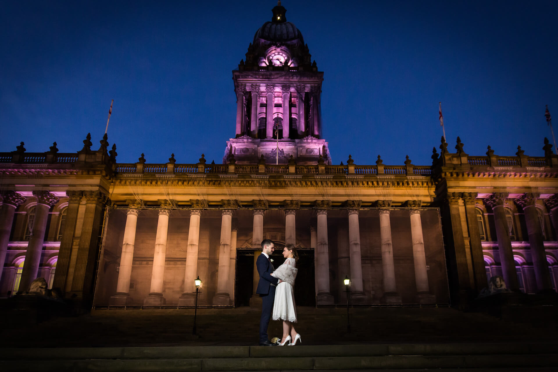 bride and groom in front of the leeds town hall at night
