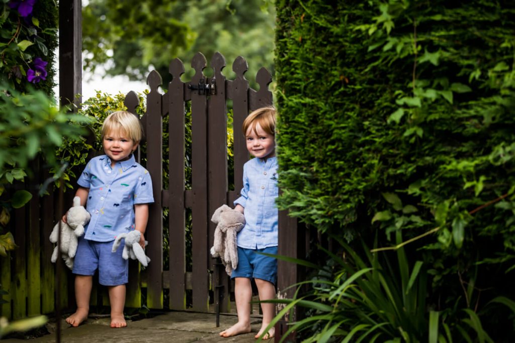 two little boys giggling behind a fence