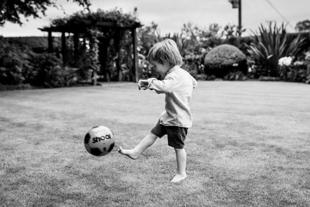 toddler kicking a football in his garden