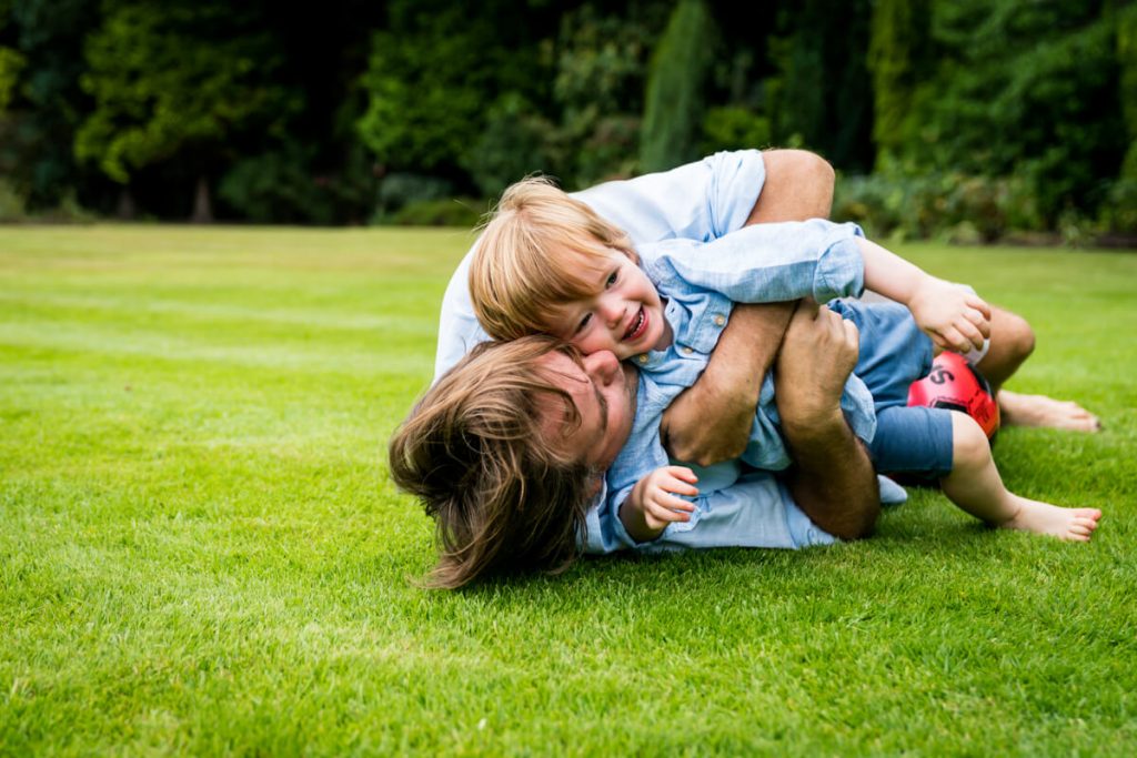 father rolling in the grass with his son