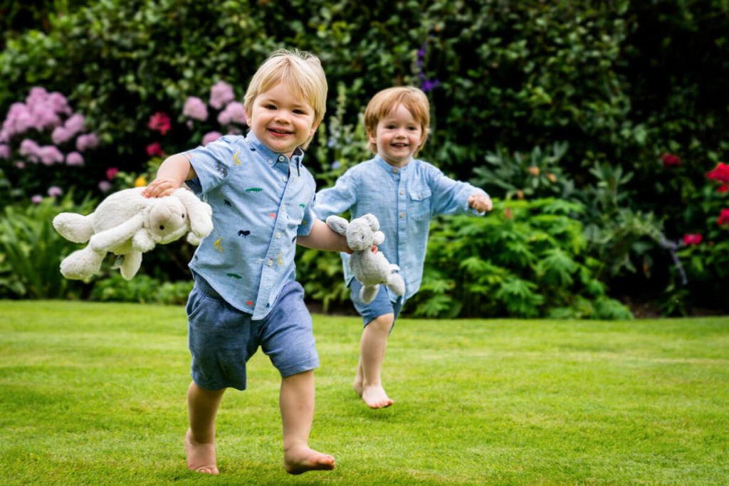 two toddlers running with their teddy bears