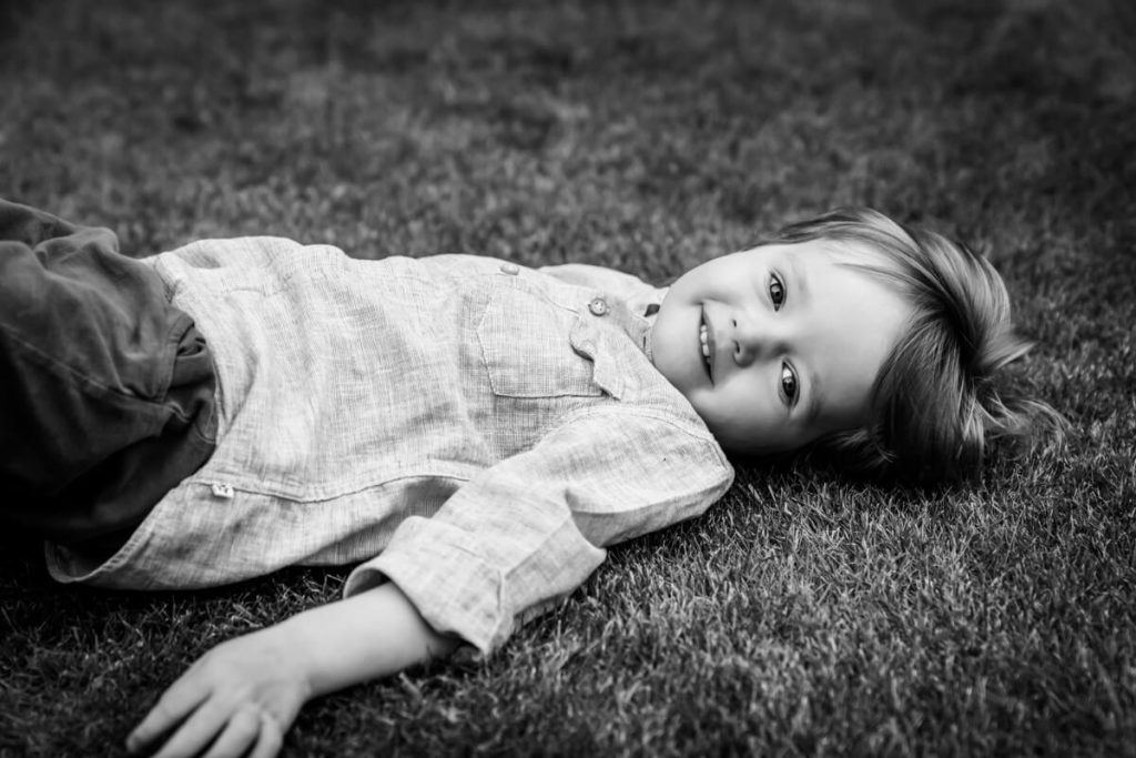 toddler lying on the grass and smiling