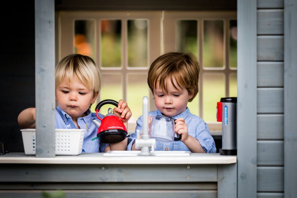 two little boys in their playhouse in a Yorkshire garden