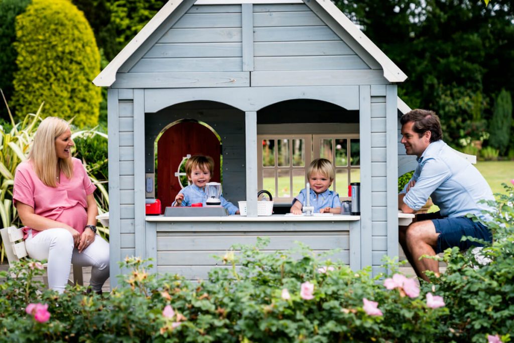 two little boys in their play house with mum and dad watching