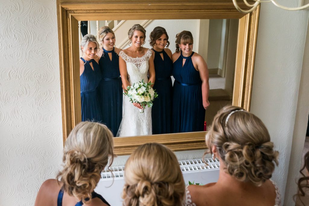 bride and bridesmaids looking in a mirror
