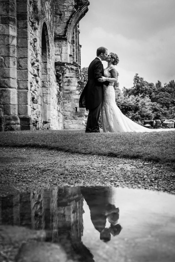 puddle reflection of the bride and groom kissing