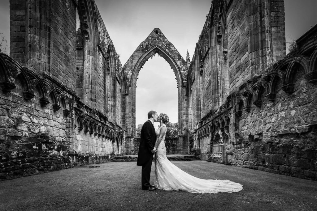 Bolton Abbey wedding couple kissing under an archway