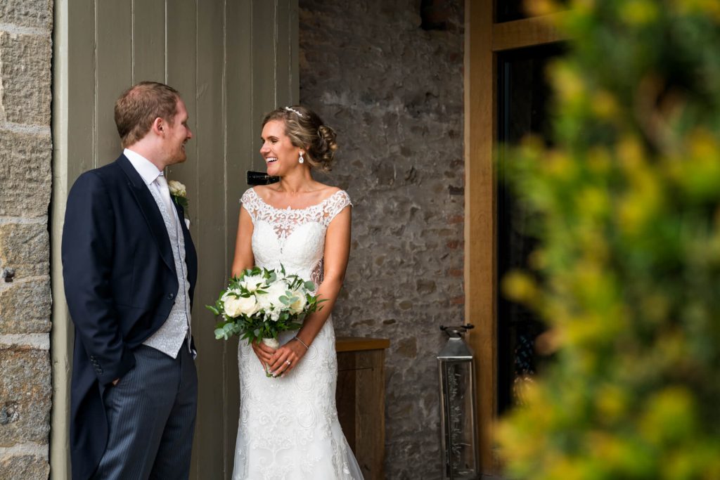 bride and groom laughing together in a doorway