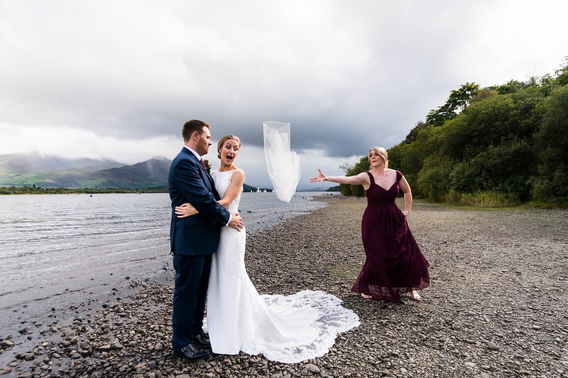 bridesmaid reaches to catch the veil as it blows away in the wind