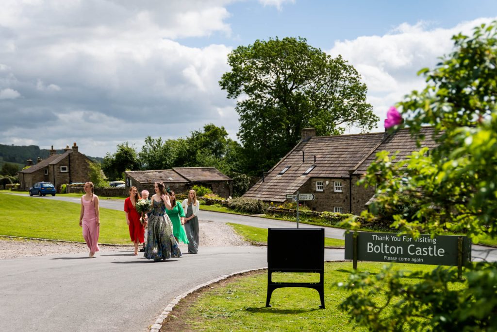 bride and bridesmaids walking along the road to Bolton Castle