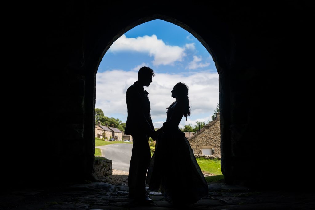 silhouette of the wedding couple under the portcullis at Bolton Castle