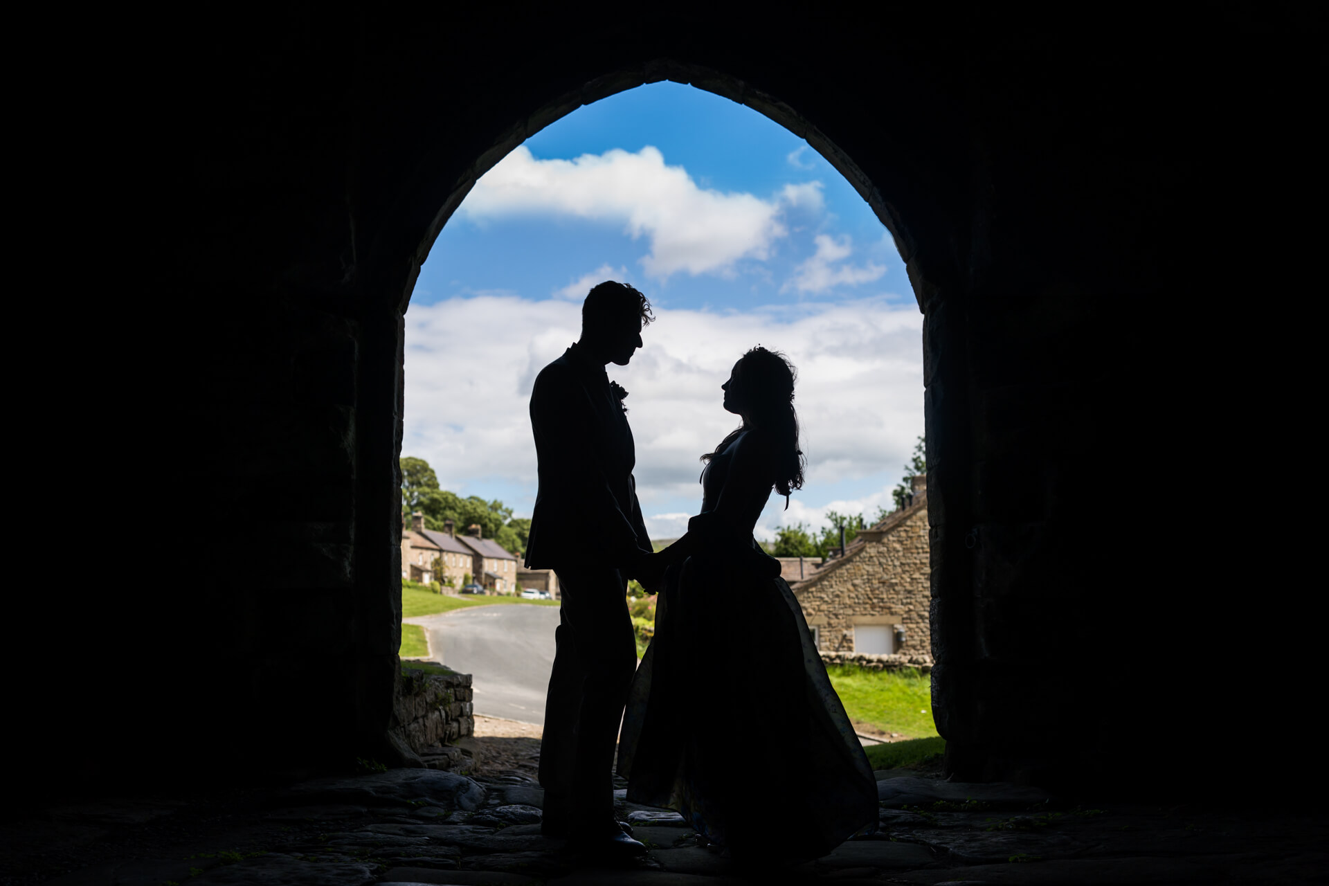 silhouette of the wedding couple under the portcullis at Bolton Castle