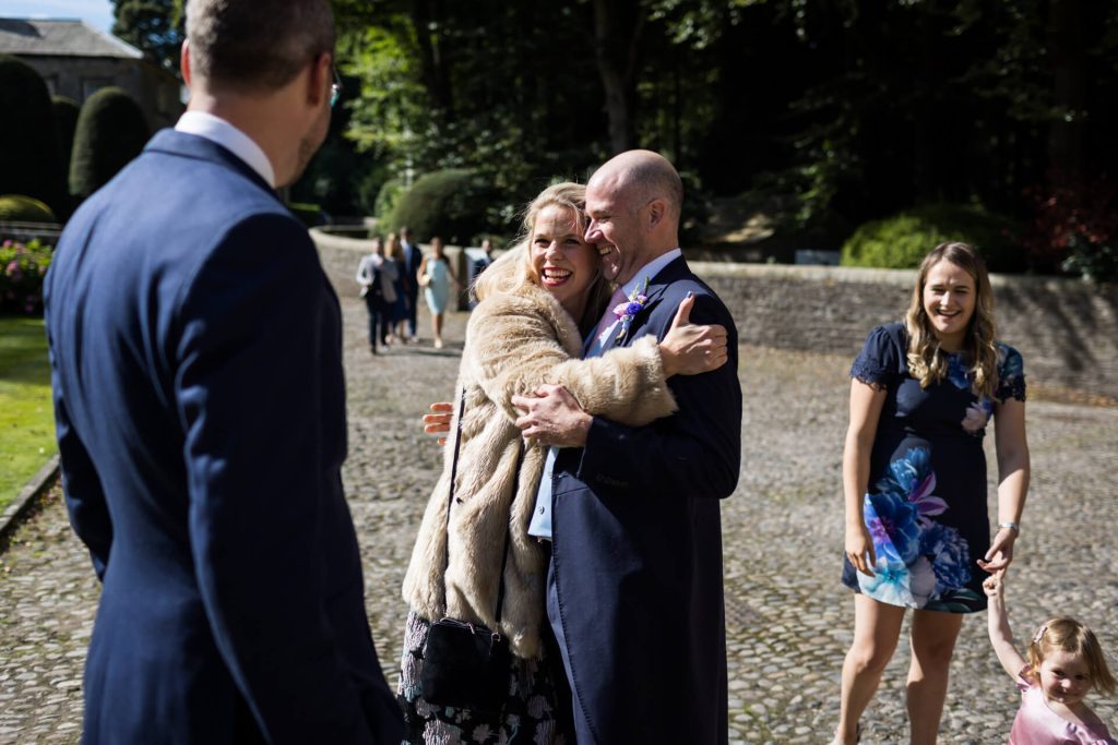 a wedding guest hugging the groom