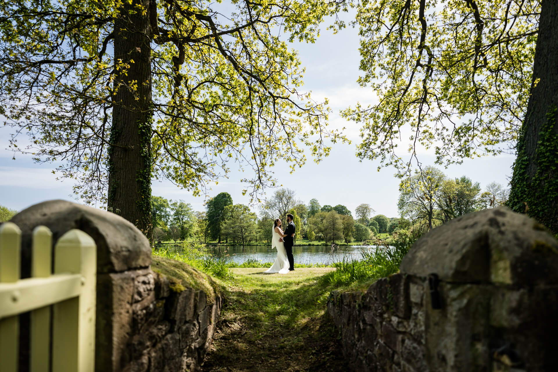 bride and groom standing in front of a lake