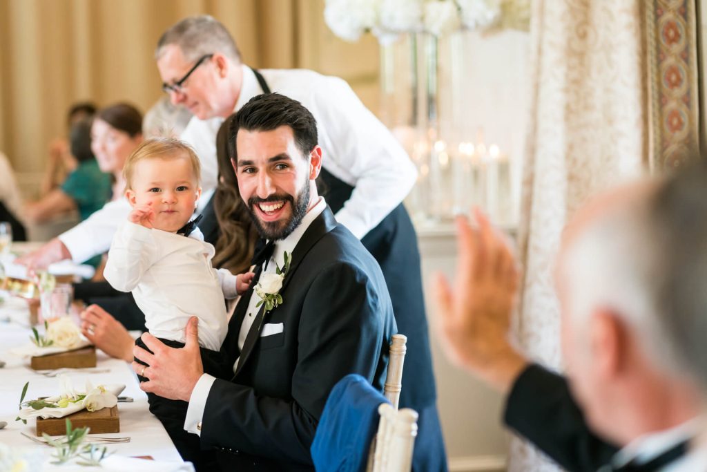 groom's little boy waving at a guest at top table