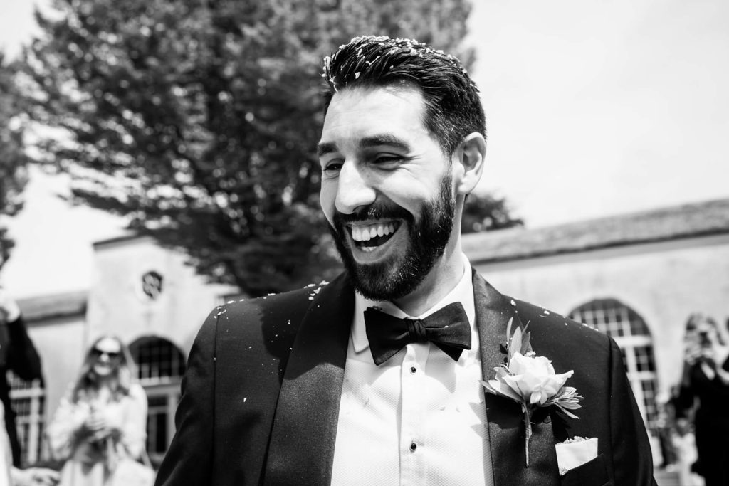 groom laughing whilst covered in confetti