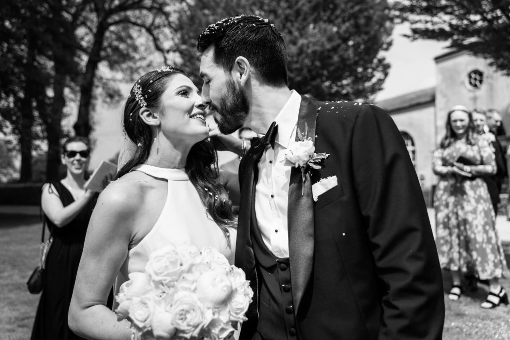 bride and groom kissing whilst covered in confetti