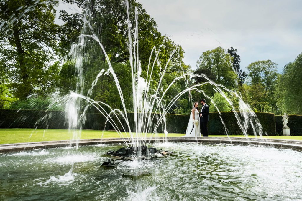wedding couple standing by the fountain at the orangery at Settrington