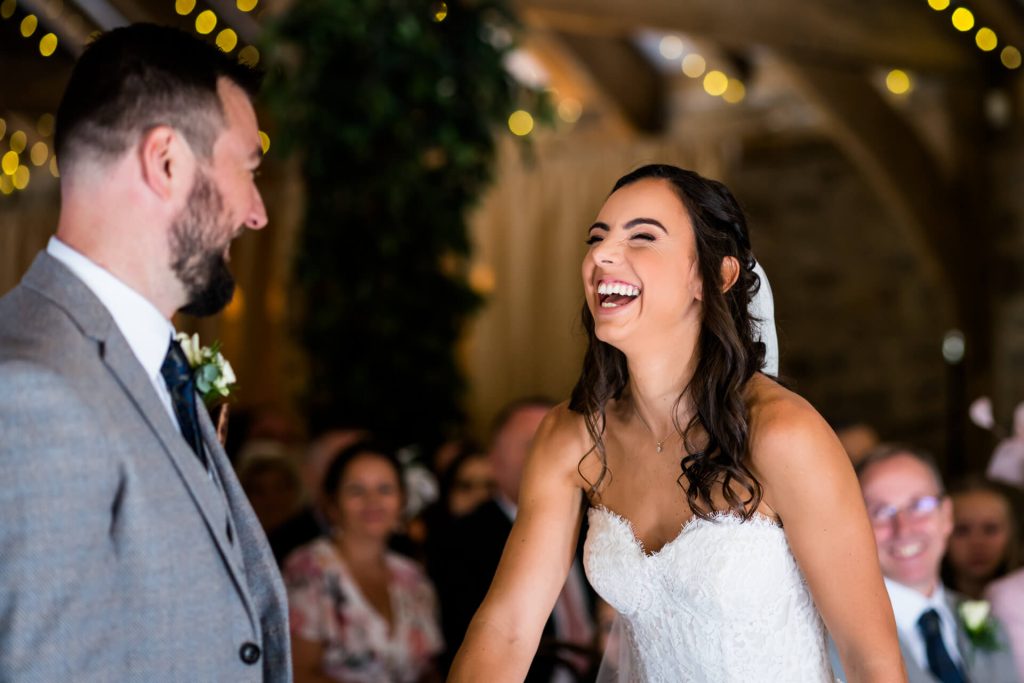 bride laughs during the wedding ceremony at The Tithe Barn