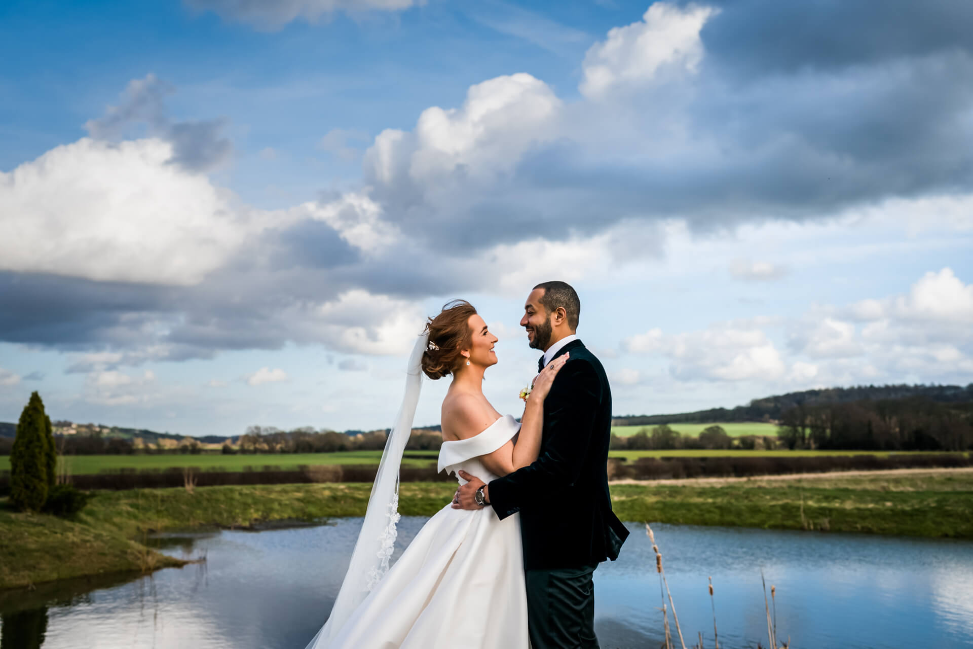 bride and groom kiss in front of a pond at Wharfedale Grange