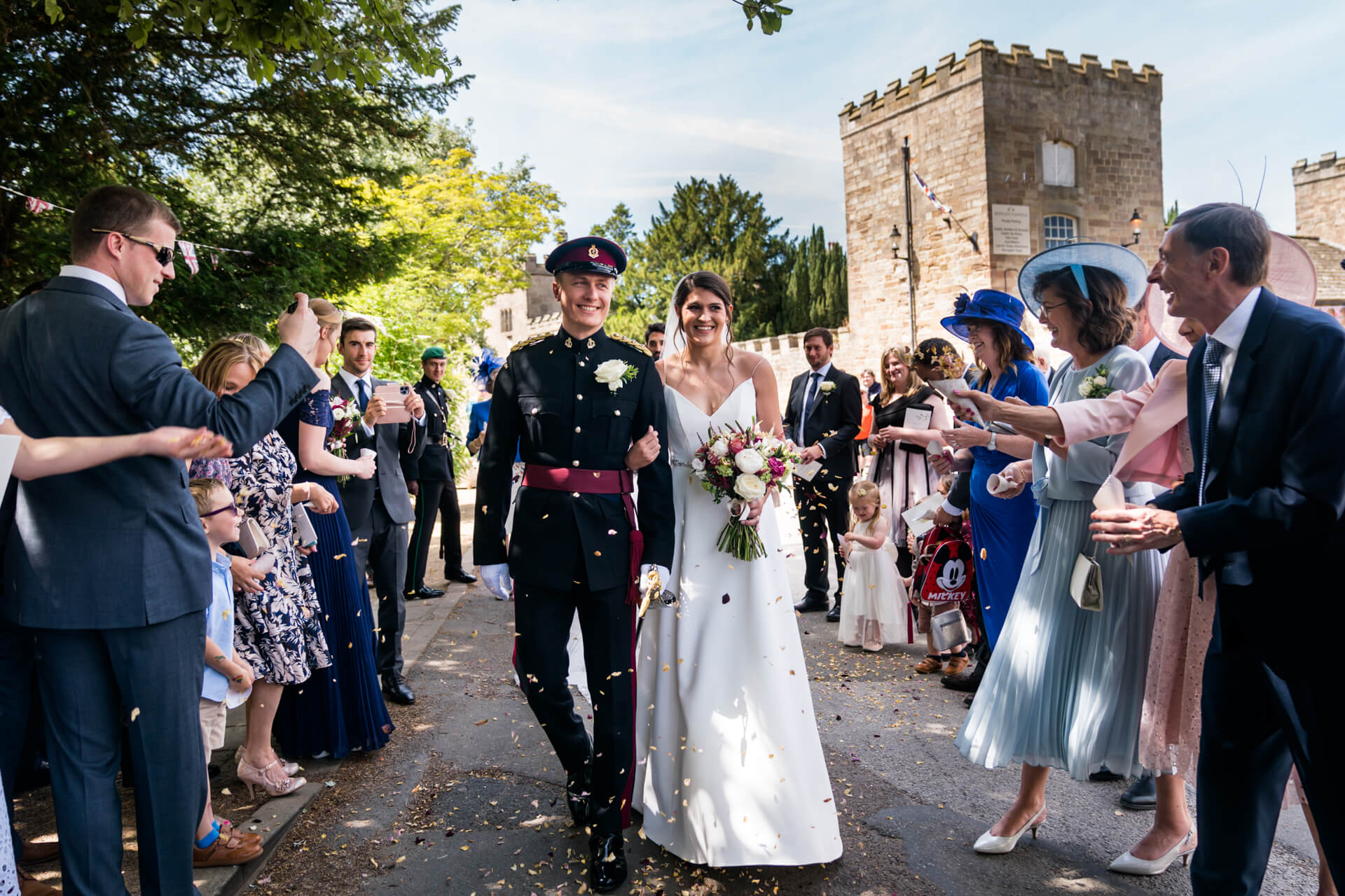wedding couple walk through a confetti tunnel outside Ripley church