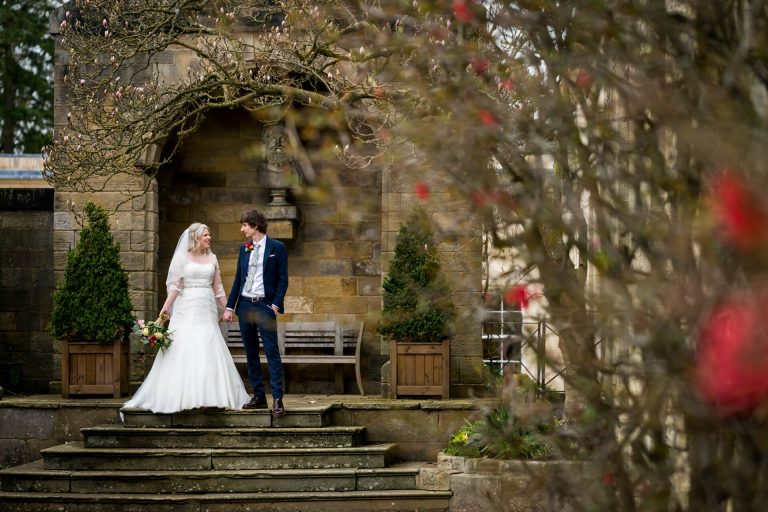 bride and groom stand in a garden archway at Rudding Park