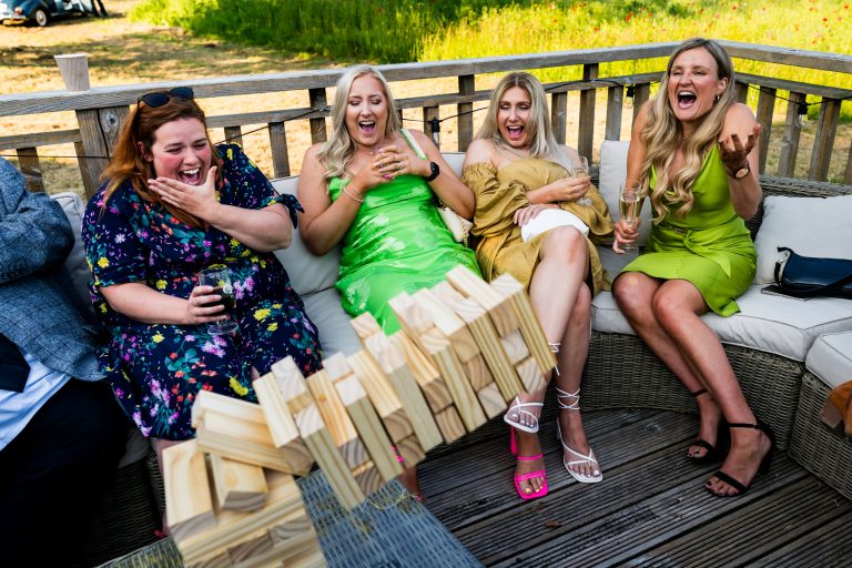Friends laughing, playing giant Jenga at outdoor wedding
