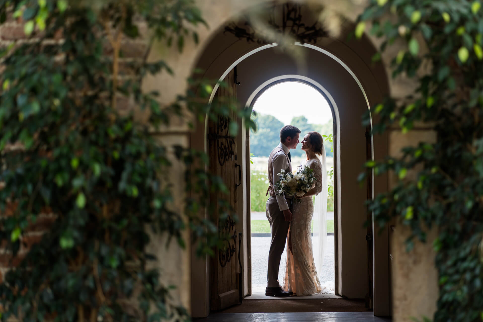 Couple kissing under archway at Middleton Lodge