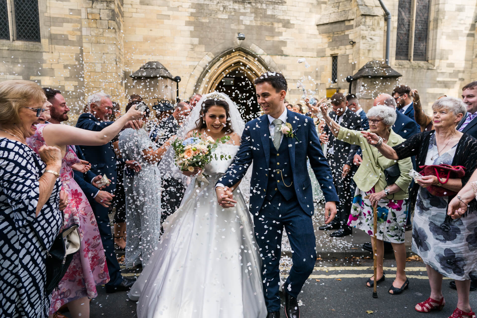Bride and groom exiting church with confetti.