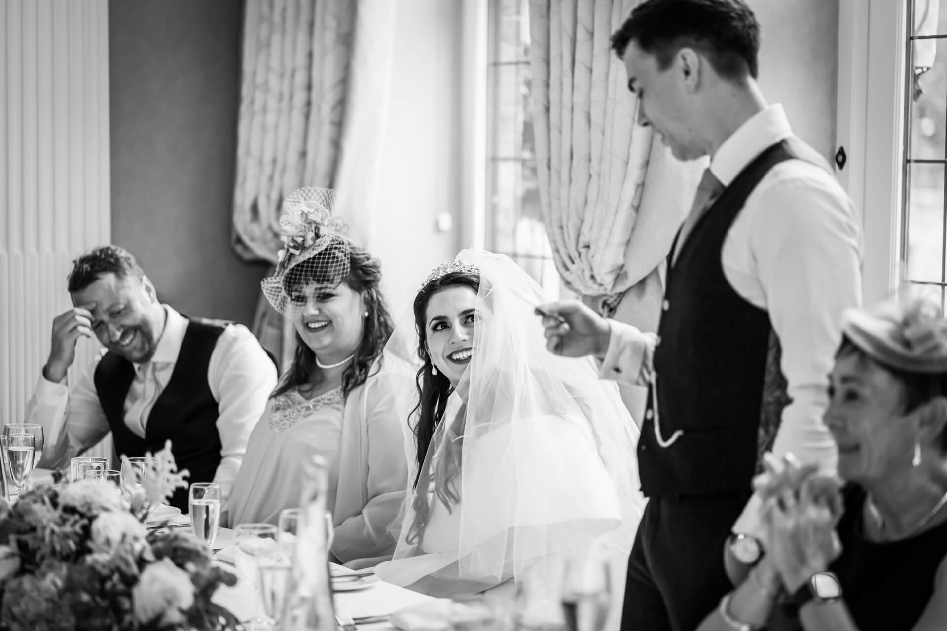 Joyful wedding reception laughter in black and white.