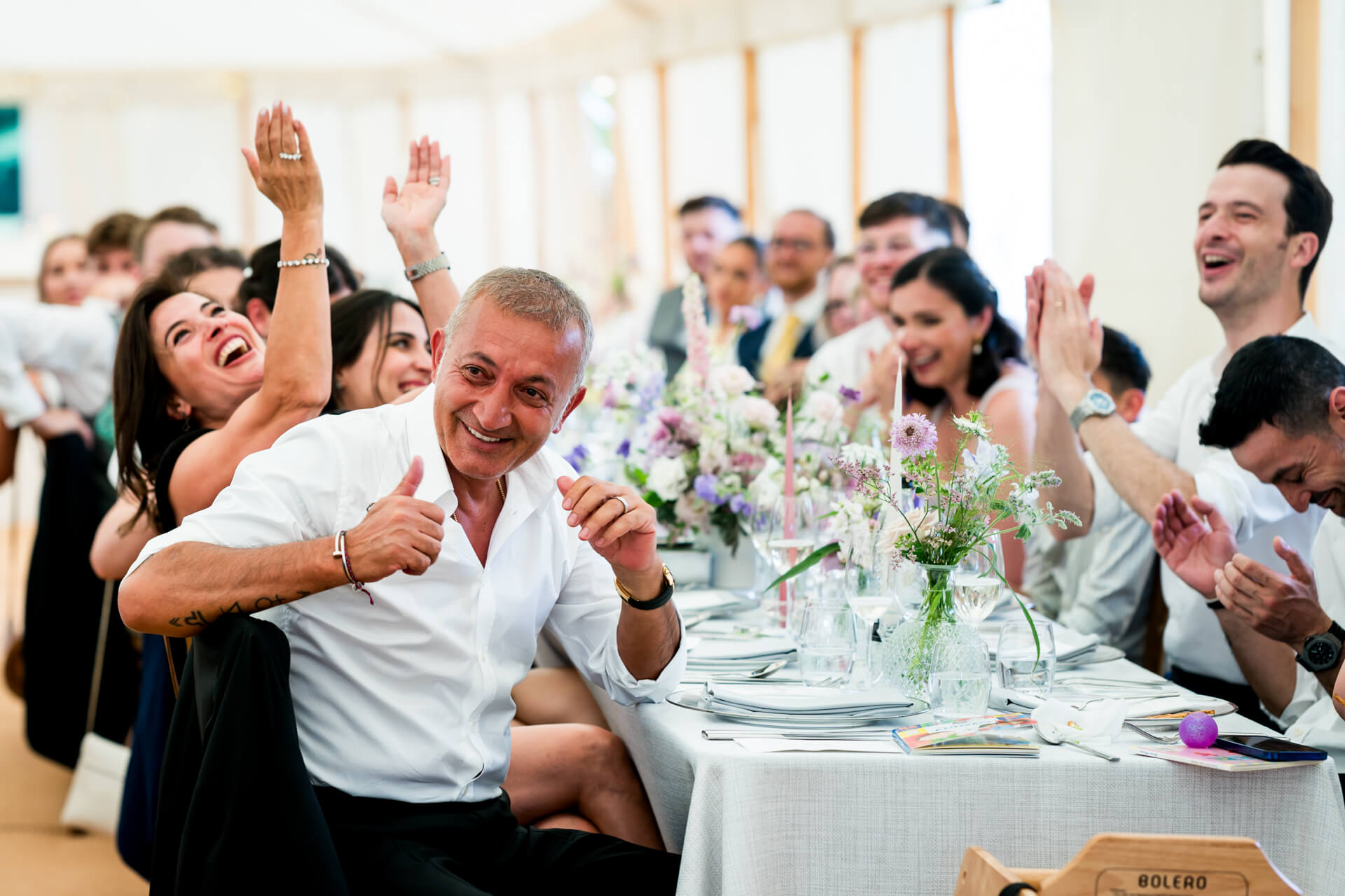 Guests clapping joyfully at wedding reception.