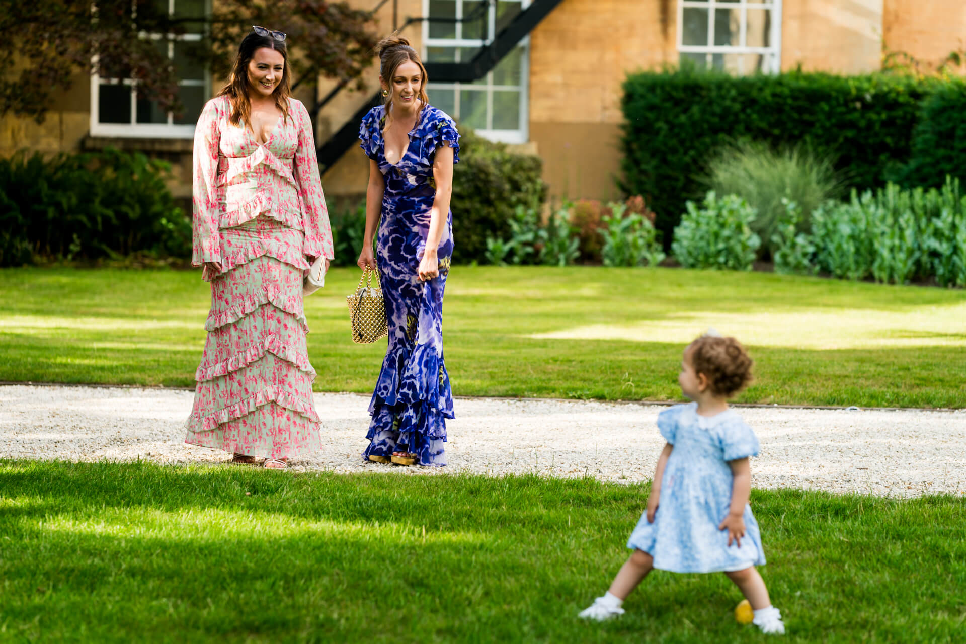 Women in dresses walking in garden with child.
