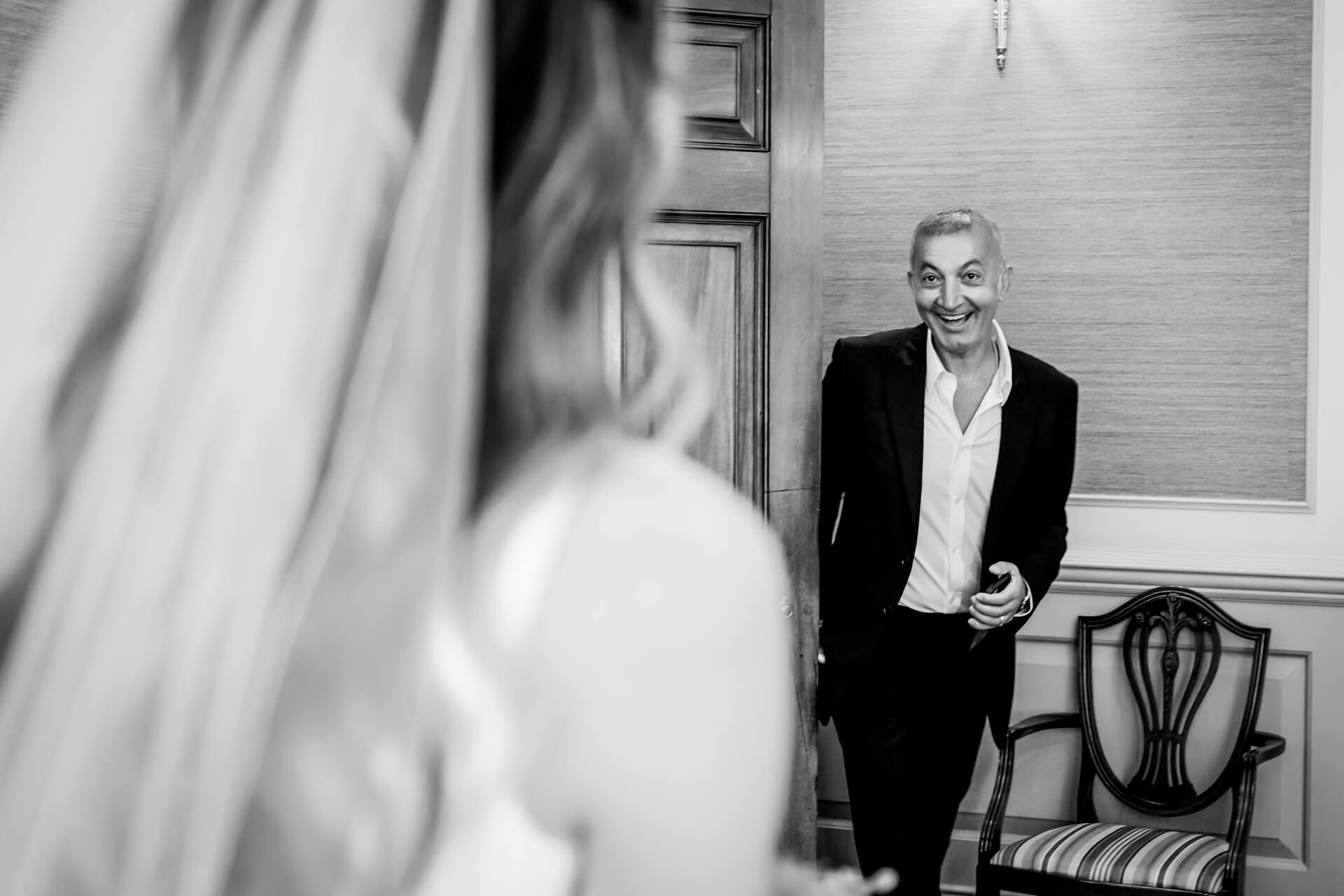 Father of the bride smiling at bride as he walks into the room