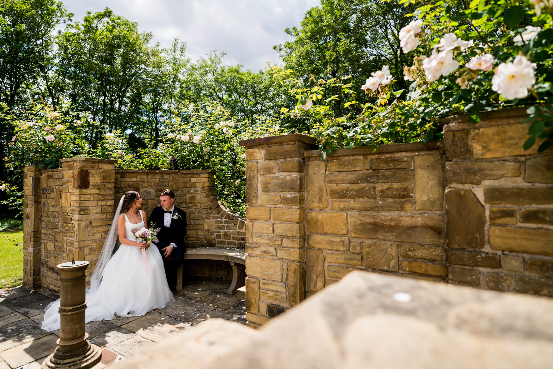 Bride and groom sitting in sunny garden at Bowcliffe Hall