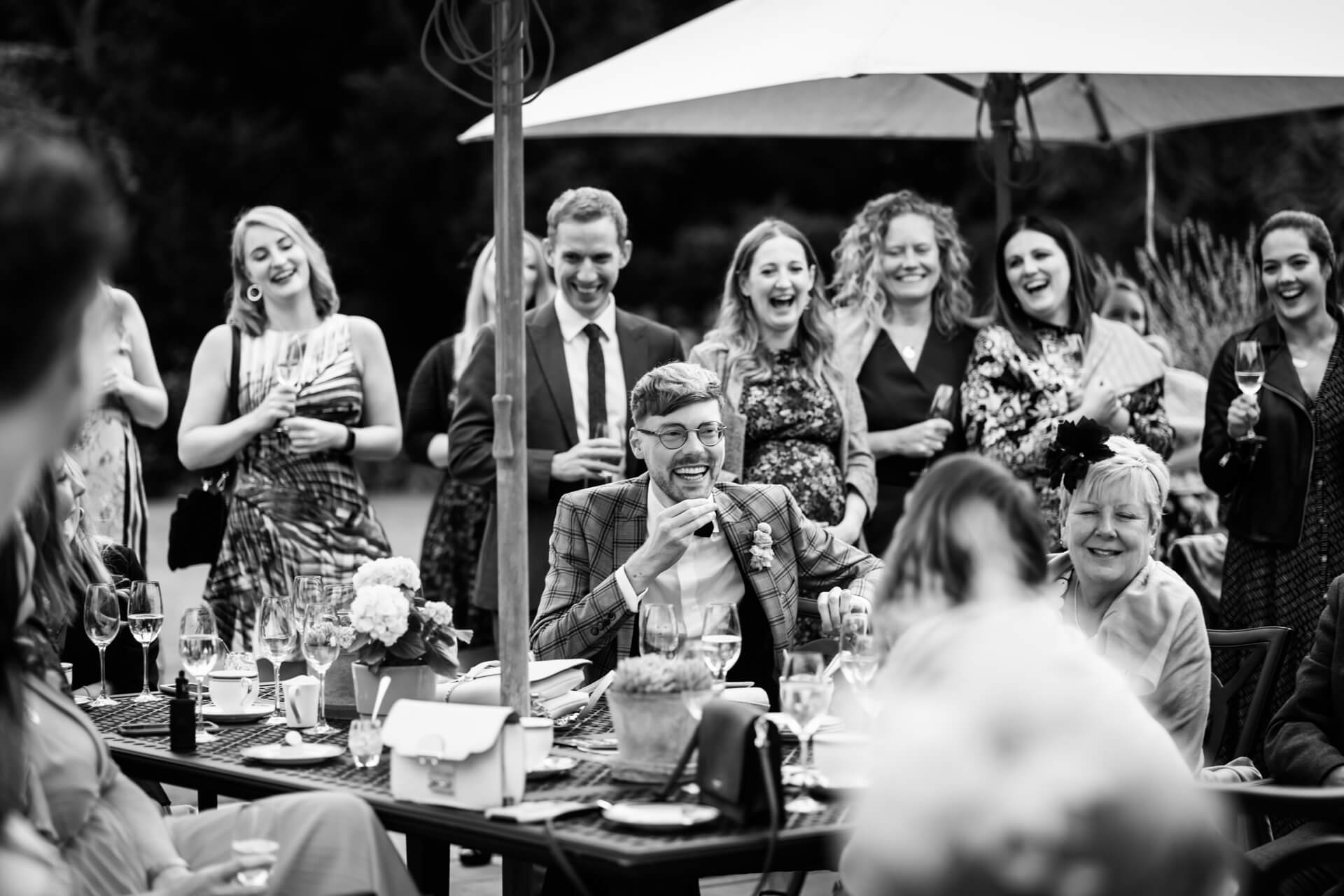 Joyful wedding guests laughing outdoors.