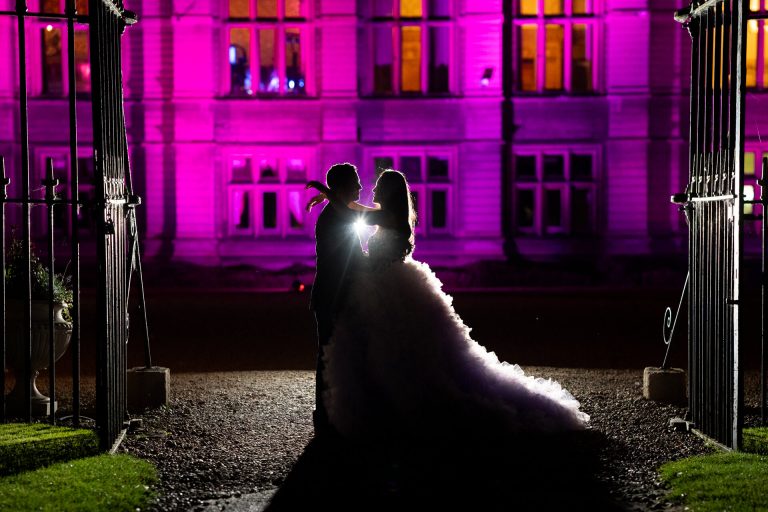 Couple silhouette outside illuminated Carlton Towers at night, wedding.
