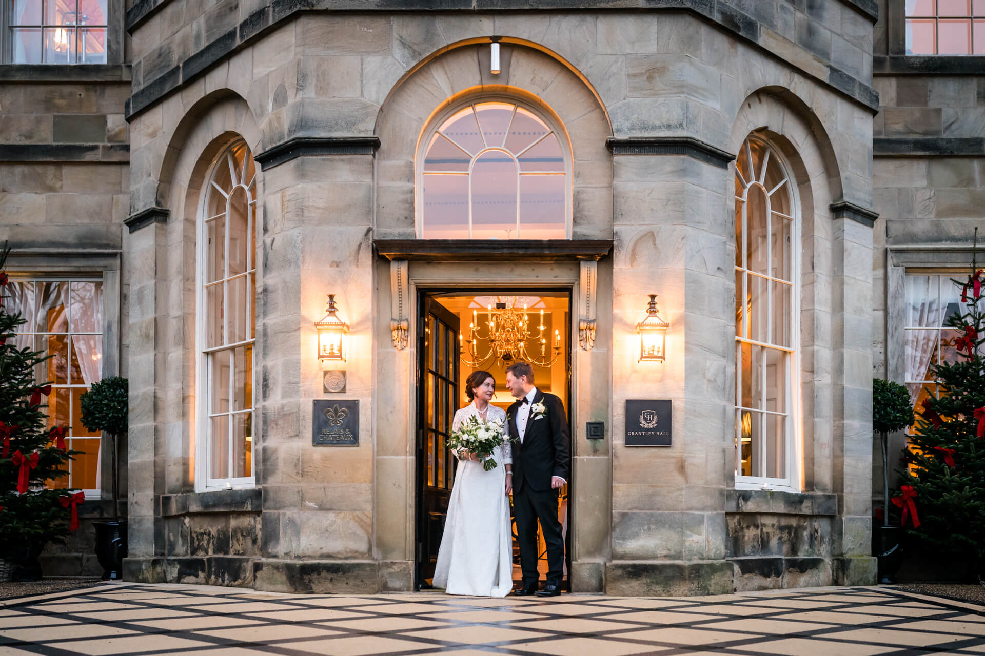 Couple at Grantley Hall entrance for wedding celebration.