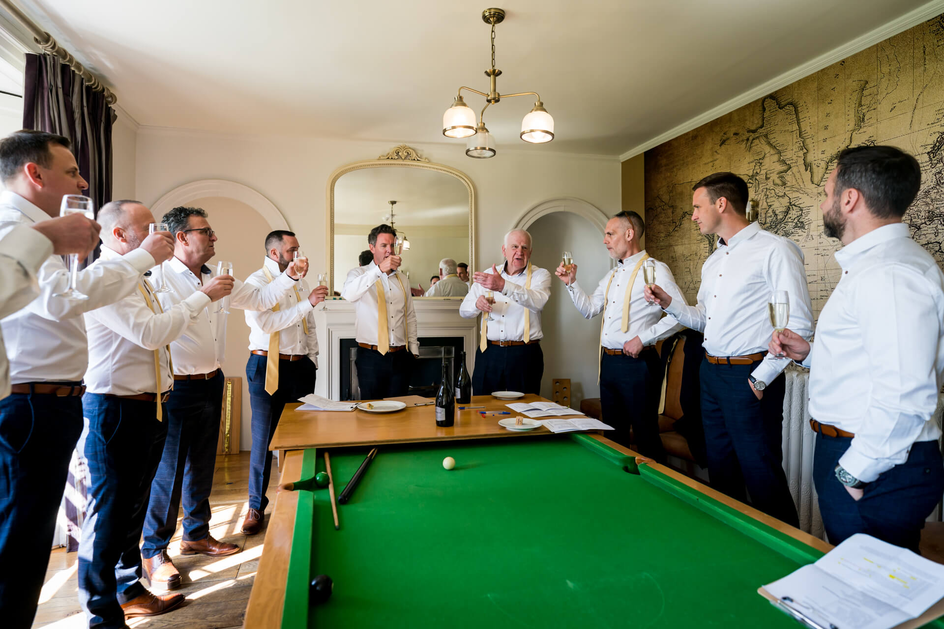 Groomsmen toasting in elegant room at Hornington Manor with pool table.