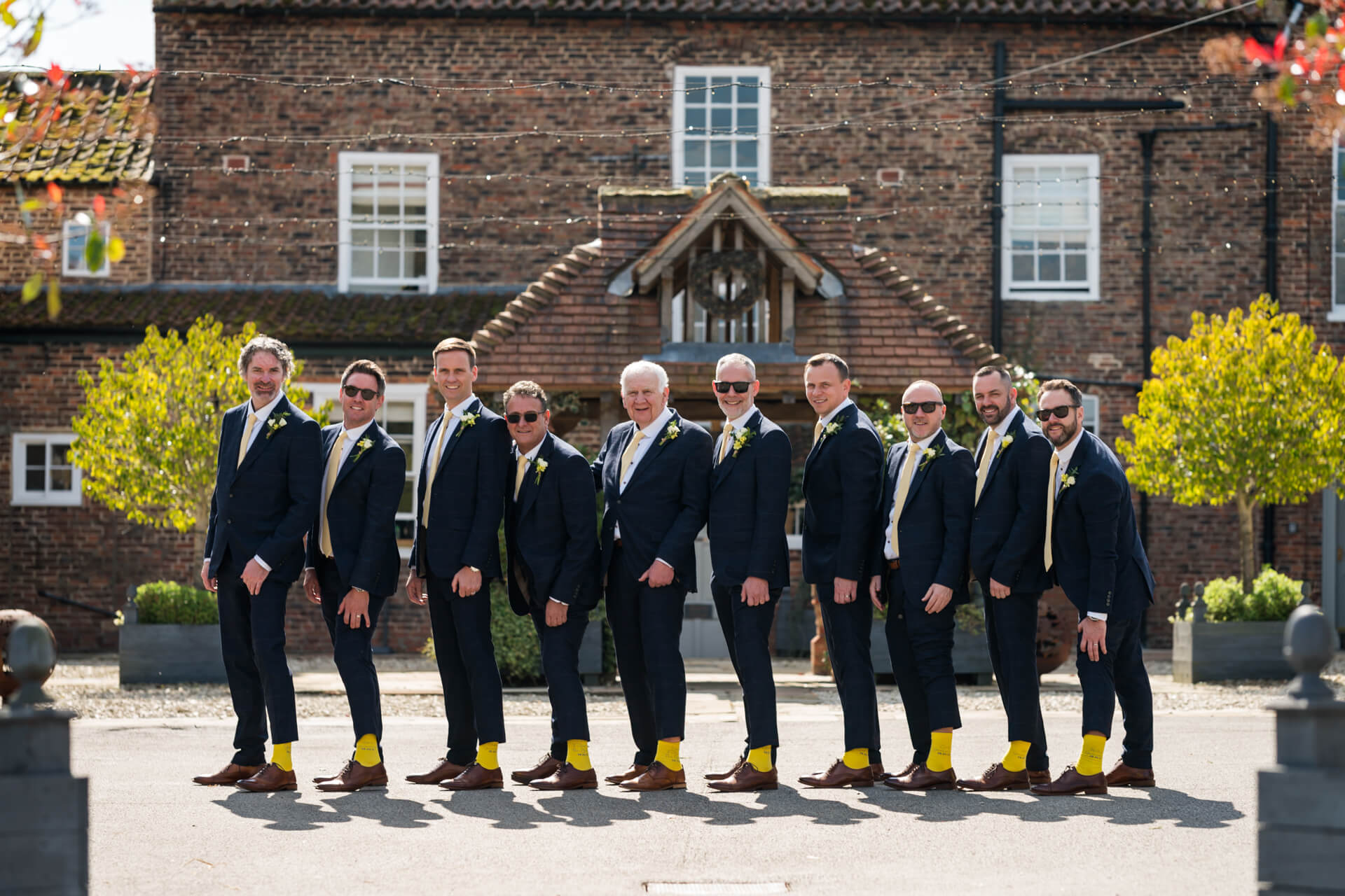 Groomsmen in suits with yellow socks outside Hornington Manor
