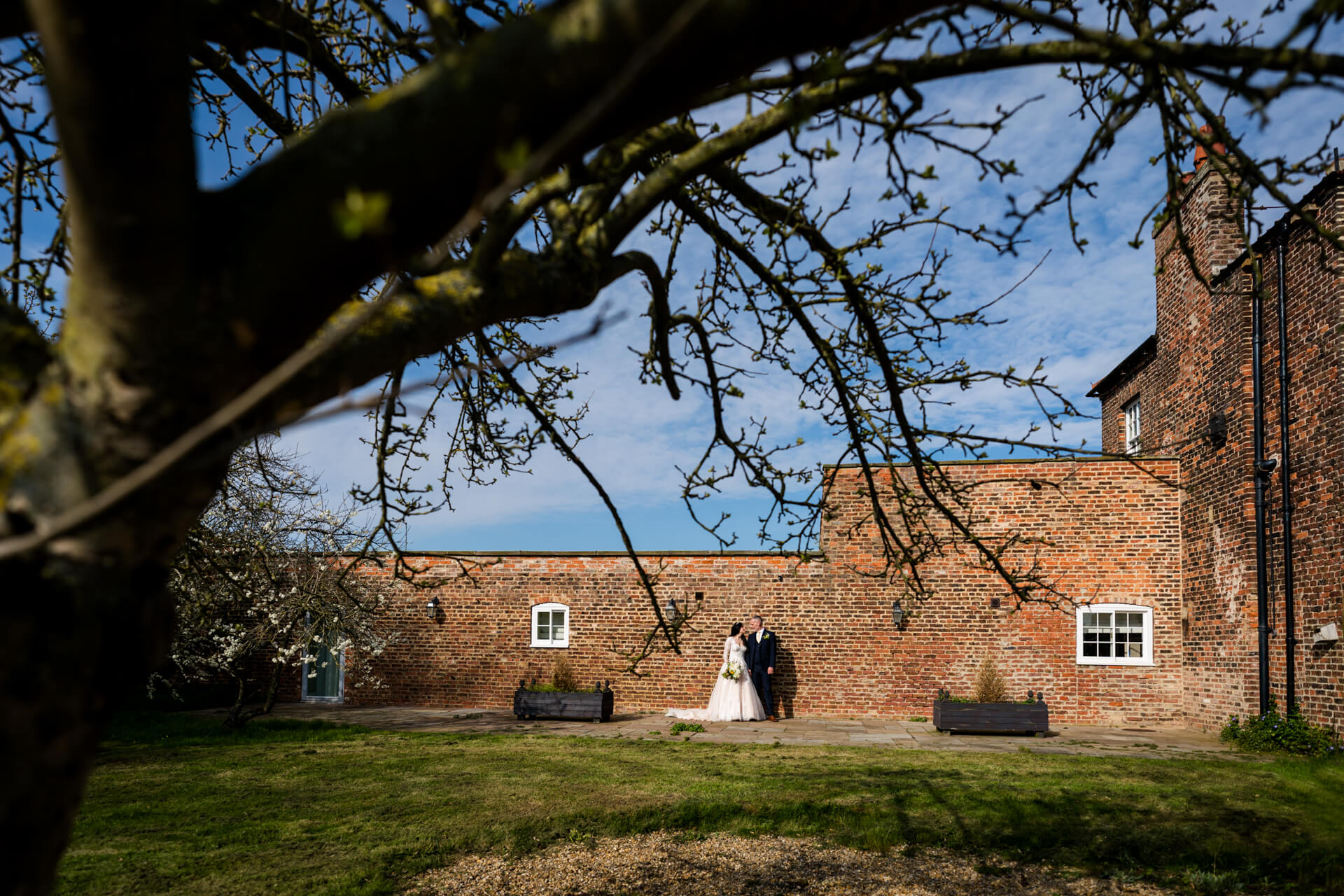 Wedding couple posing near brick building, spring wedding scene at Hornington Manor
