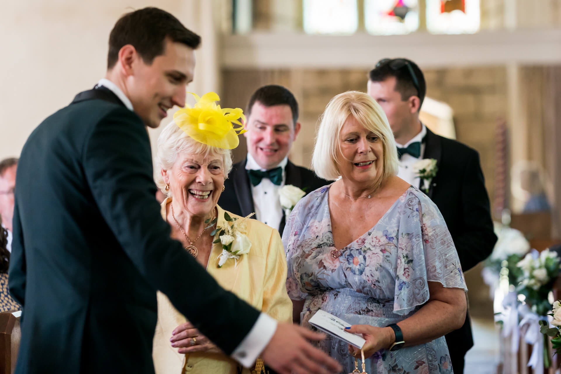 Wedding guests smiling and interacting in church.
