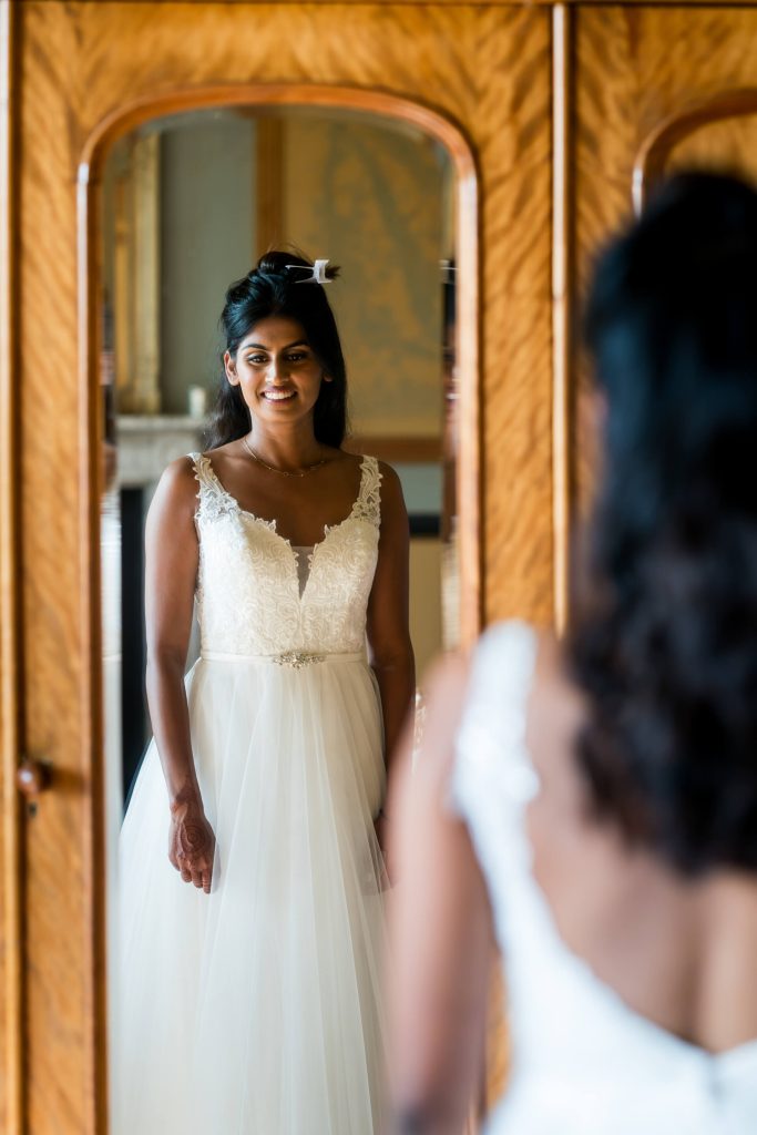 Bride reflecting in mirror, elegant wedding dress.